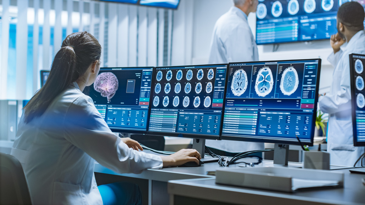 Neurologists/Neuroscientists Surrounded by Monitors Showing CT, MRI Scans