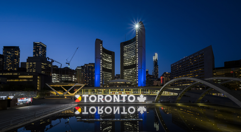 Toronto City Hall and Nathan Phillips Square with the large Toronto sign lit up.