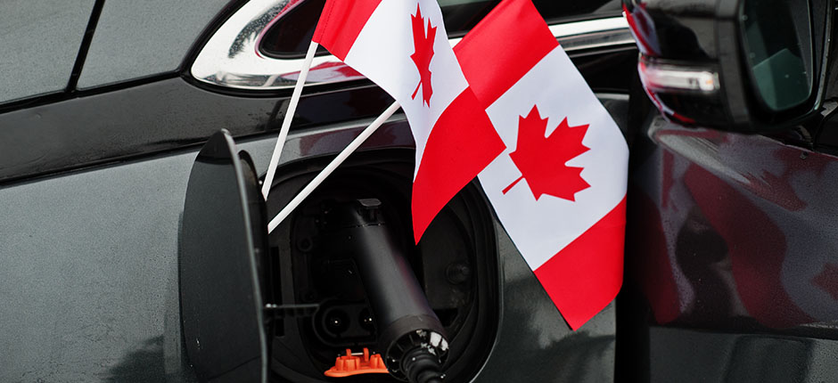 Canadian flags displayed alongside an open charging port on an electric vehicle.