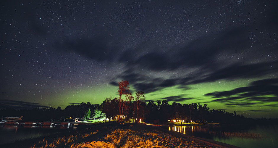 The Northern Lights show a green glow over the horizon.