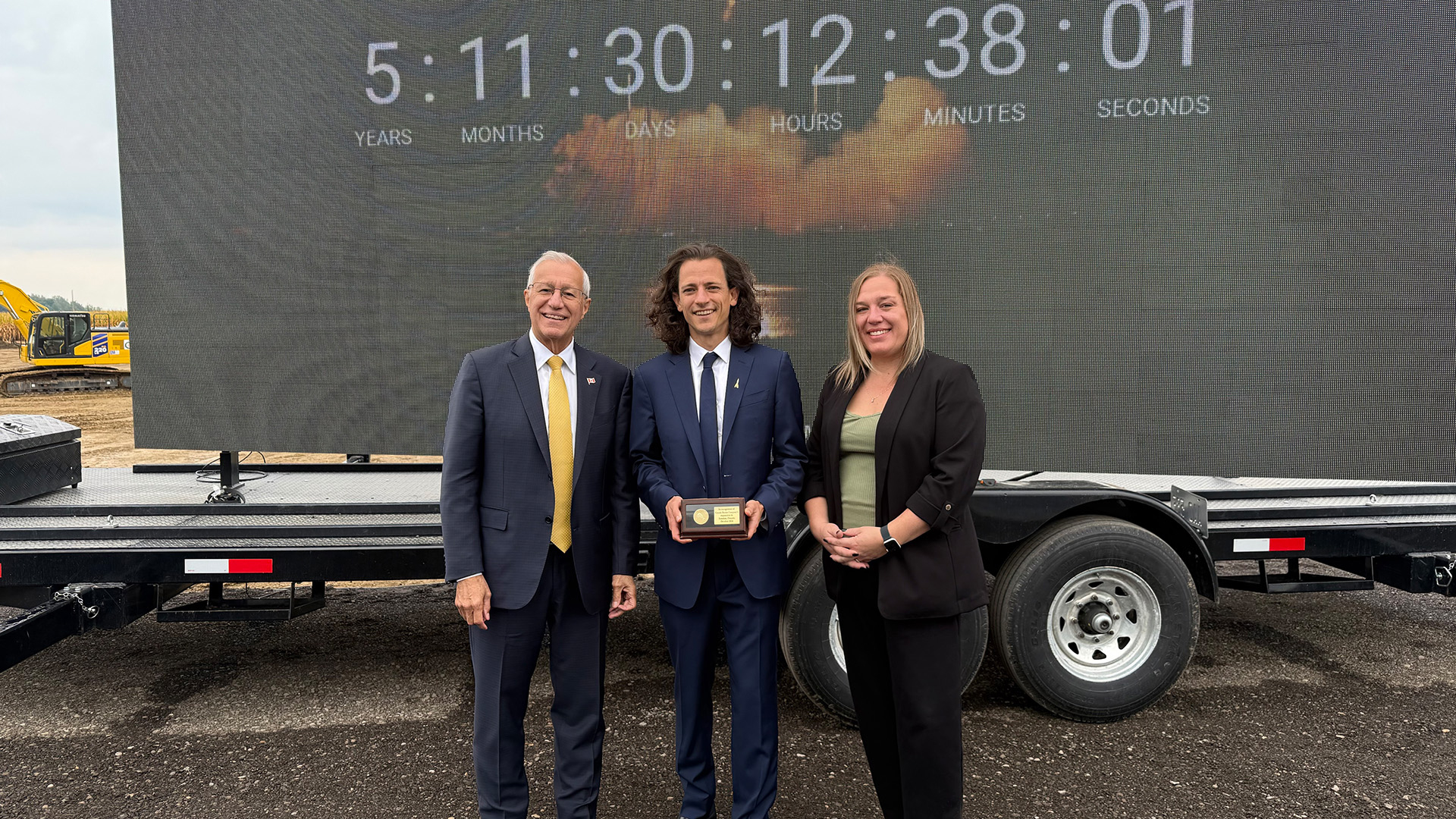 Minister Fedeli, Canada Rocket Company CEO Hugh Kolias, and Invest Ontario VP Heather Potter stand beside a clock moving six years closer to the facility's opening. 