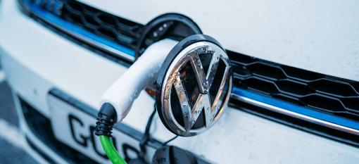 Electric Volkswagen vehicle, charging through a port on the front behind the VW emblem.